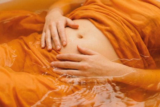 Ventre envolto em luz alaranjada e fluida, representando a relação entre chakras e emoções e o centro do prazer.