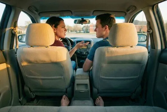 Casal discutindo no carro com pés firmes no tapete e discretos exercícios de respiração para como se acalmar em uma discussão.