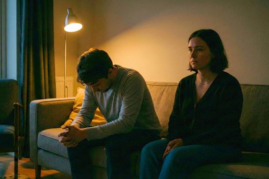 Casal em momento de silêncio reflexivo na sala, exemplificando como aceitar as dificuldades é parte de saber como manter viva e como recuperar a intimidade no relacionamento.