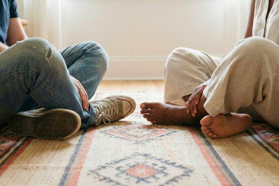 Duas pessoas sentadas no chão ao mesmo nível, simbolizando o respeito à diversidade e a segurança em vivências tântricas.