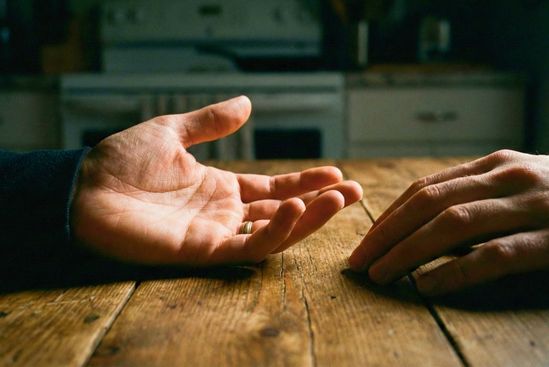 Mãos se abrindo sobre uma mesa em gesto de honestidade e entrega, simbolizando a coragem de assumir a falta de intimidade no relacionamento.