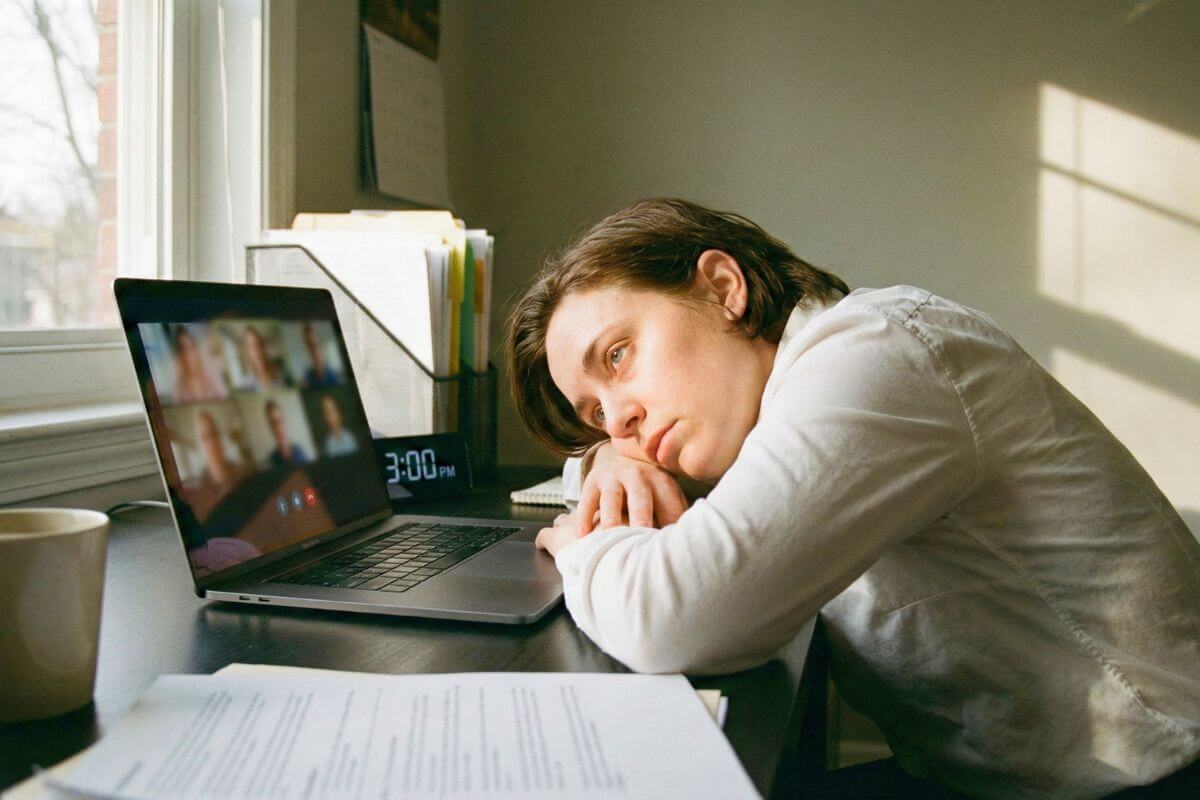 Profissional exausto em reunião, tentando descobrir como recuperar a energia por causa do cansaço emocional no trabalho.