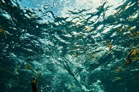 Visão submersa em água turbulenta com bolhas, simbolizando a sensação de retraumatização e perda de controle.