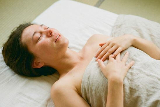Corpo deitado no futon respirando fundo durante sessão, sugerindo diferentes tipos de massagem tântrica com presença.