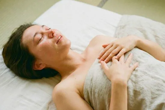 Corpo deitado no futon respirando fundo durante sessão, sugerindo diferentes tipos de massagem tântrica com presença.