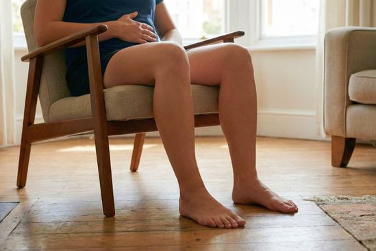 Pessoa sentada com pés firmes no chão e mão na barriga, praticando como lidar com o medo.