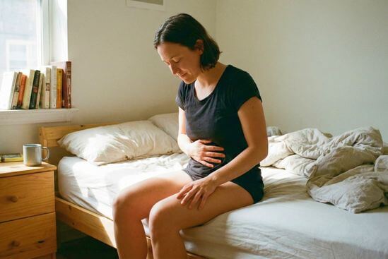 Pessoa sentada em casa, olhos fechados, praticando presença corporal ao sentir uma única sensação com calma.