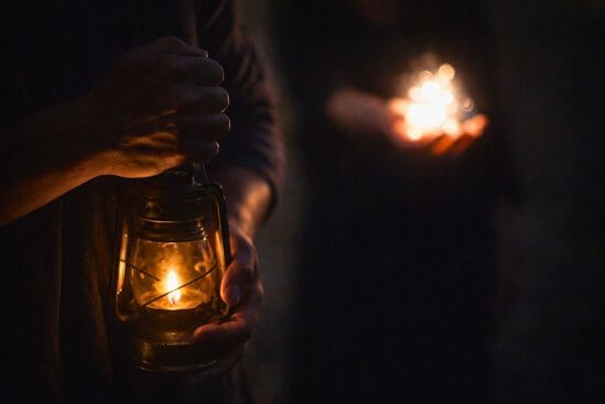 Mão guarda uma luz discreta enquanto outra oferece brilho intenso, sugerindo maturidade espiritual.